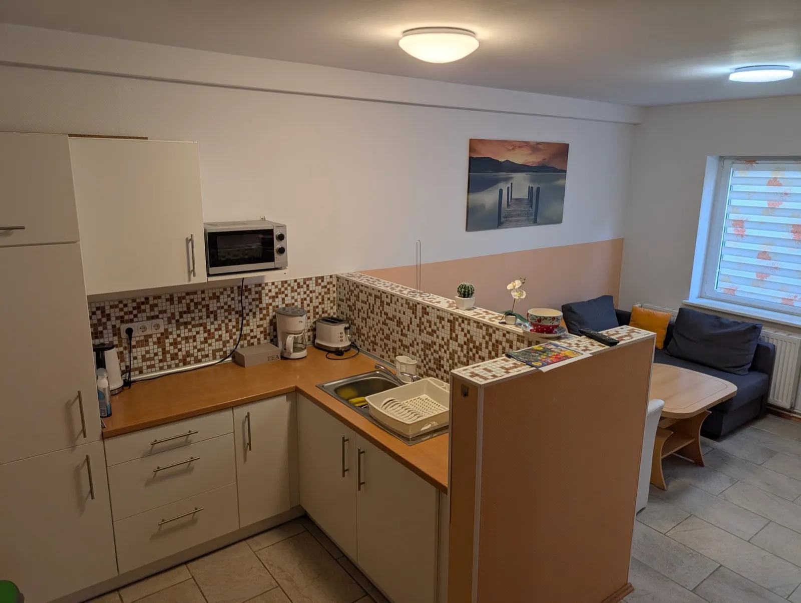 Küche der Wohnung Eiche in Erkner mit Mikrowelle, Kaffeemaschine, Toaster und Wasserkocher, zum Wohnbereich hin offen