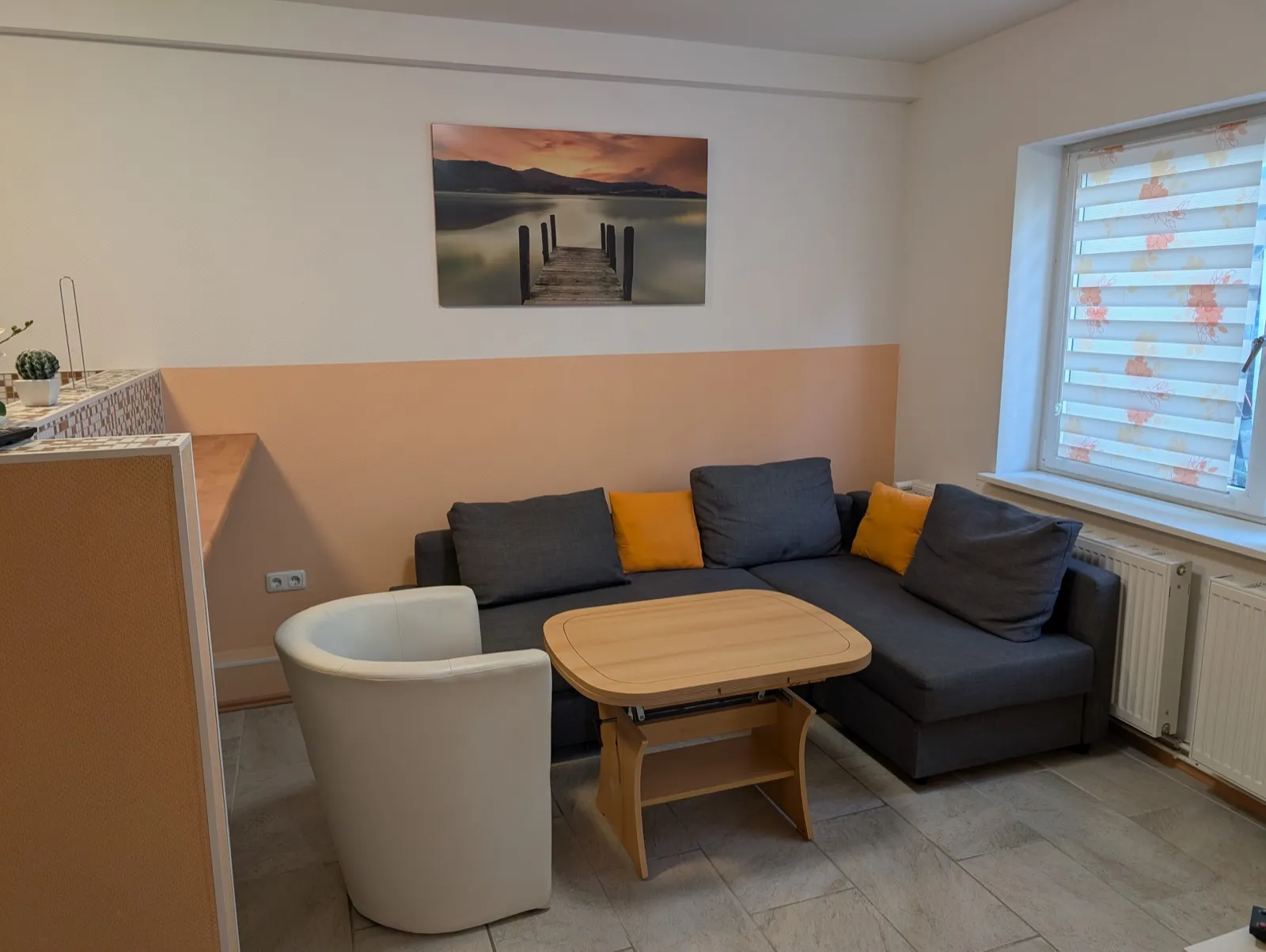 Wohnung Eiche in Erkner: Wohnbereich mit Ecksofa, Sessel und Tisch am Fenster